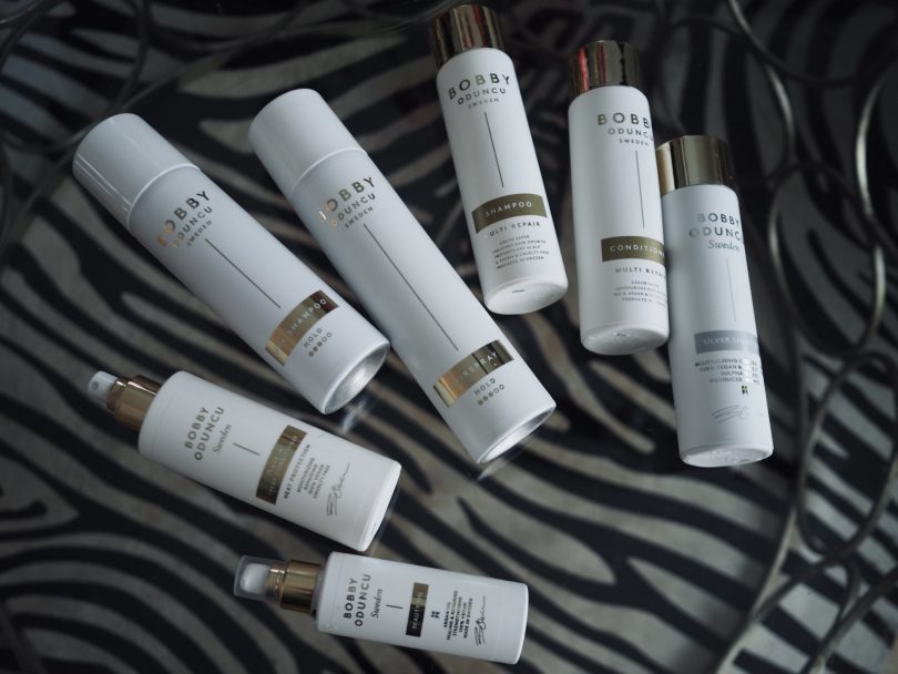 Produkter från Bobby Oduncu Sweden ligger på ett glasbord med en zebra-matta under. Torrschampot, balsam, schampo, beauty oil, värmeskydd, silverschampo, hårspray.